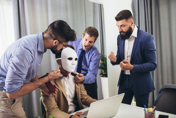 Happy colleagues having fun at meeting in boardroom, sitting at table together, sharing ideas, discussing project strategy. Businessman hidden behind the mask - Photo, Image