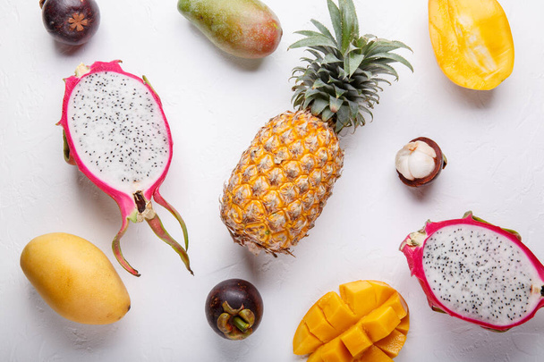 Tropical fruits on white. Dragon fruit, mango, pineapple, mangosteen, banana, coconut. Healthy food background. Summer concept. Top view, flat lay. - Photo, Image
