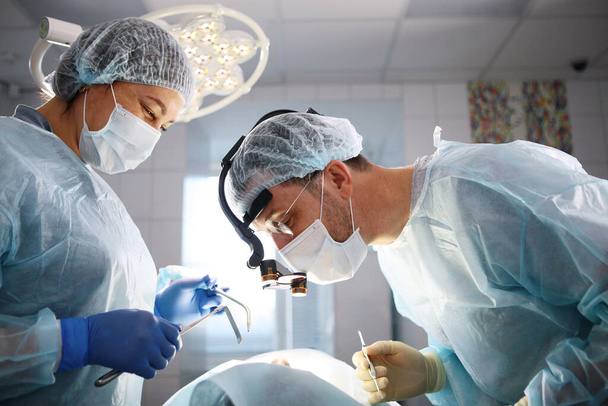 Dental surgery. The surgeon and the assistant. The patient is unrecognizable. Modern dentistry. Photo in the operating room. The concept of healthcare. - Foto, Bild