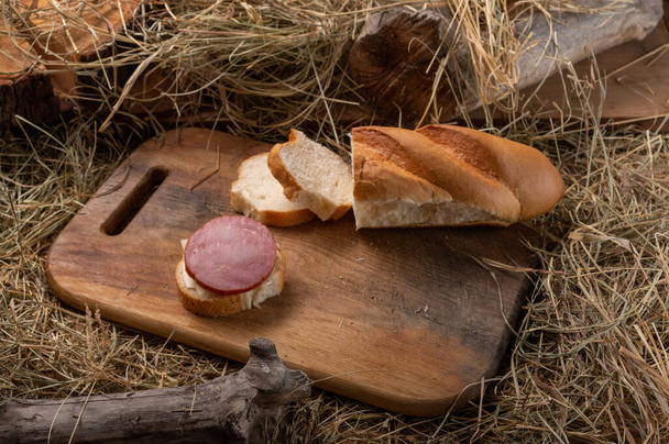 Sandwich with white bread and sausage. Hay and wood. Top. - Photo, Image