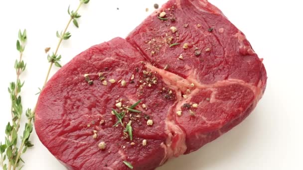 close-up van roterend pittig rauw rundvlees steak vlees op witte achtergrond, bovenaanzicht - Video