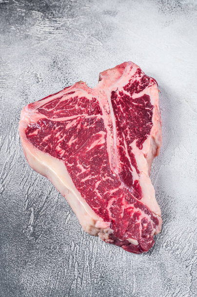 Nyers T-bone vagy porterhouse steak a konyhaasztalon. Fehér háttér. Felülnézet - Fotó, kép