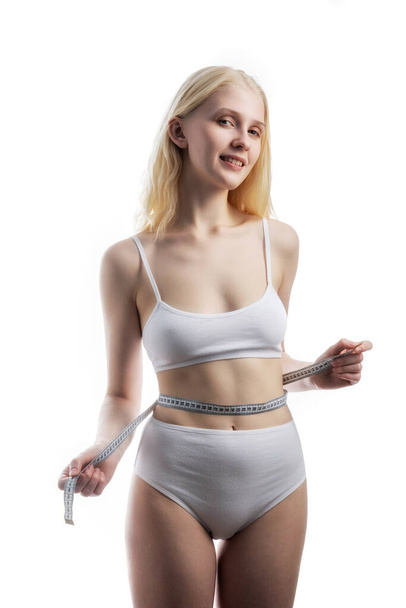 one attractive Caucasian girl in white panties with a centimeter measuring hips and waist on white background - Foto, Imagen