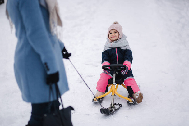 Little girl enjoying sledding. Mom sledding her little daughter. Family vacation on Christmas eve outdoors - Photo, Image