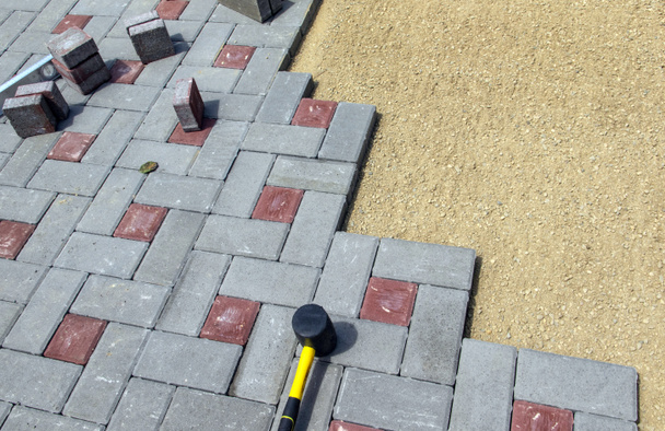 Un constructeur installe des blocs de béton pour les trottoirs dans la cour d'une maison de campagne. Concentration sélective. - Photo, image