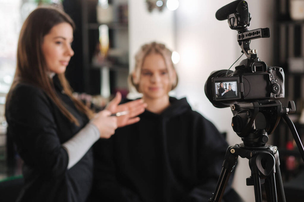 Nainen meikki houkutteleva vaaleat hiukset nainen studiossa. Digitaalikameran valikoiva tarkennus meikkitaiteilijan kanssa soveltamalla kosmetiikkaa kauniiseen malliin - Valokuva, kuva