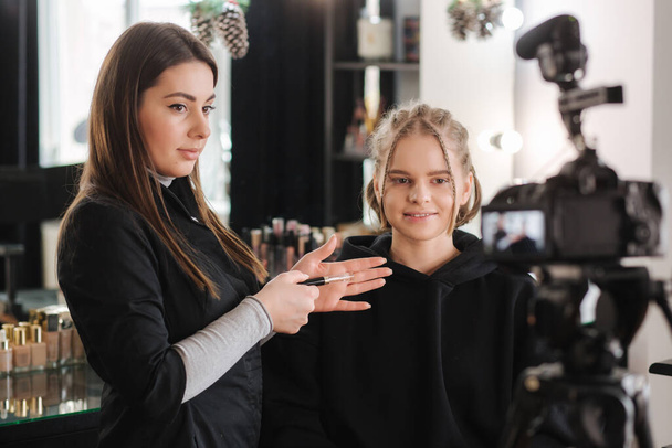 Woman make makeup for attractive blond hair woman in studio. Video of makeup artist applying cosmetics for beautiful model - Photo, Image