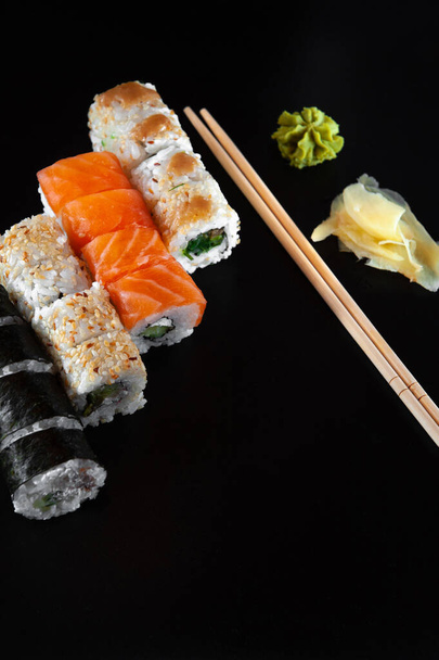 Ensemble de rouleaux de sushi servis sur ardoise de pierre noire sur fond sombre - Photo, image