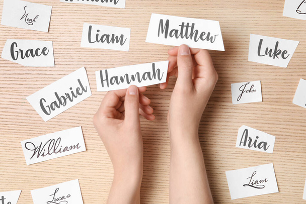 Woman choosing baby name at wooden table, top view - Photo, Image