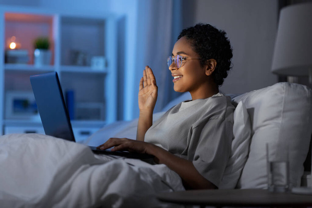 woman having video call on laptop in bed at night - Zdjęcie, obraz