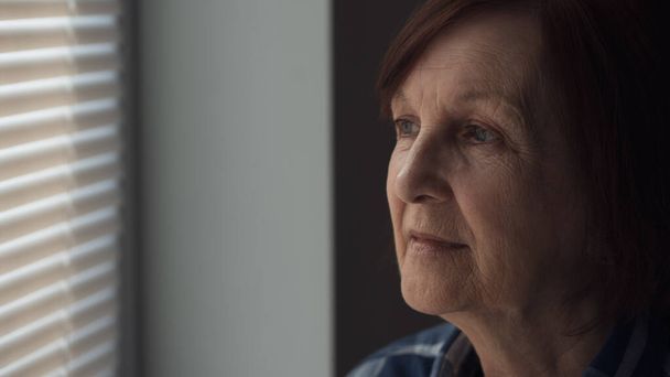 Detailní portrét starší ženy s demencí, která se dívá oknem. - Fotografie, Obrázek
