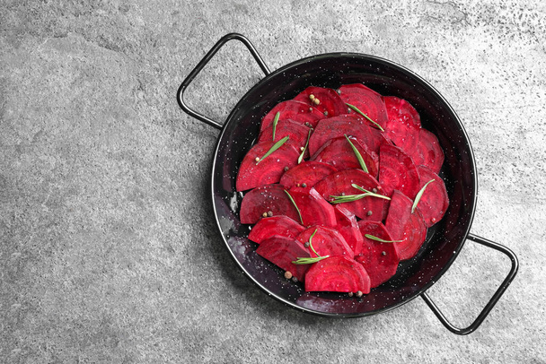Slices of raw beetroot in wok pan on grey table, top view - Фото, изображение