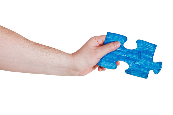 чоловіча рука з пофарбованою синьою частиною головоломки
 - Фото, зображення