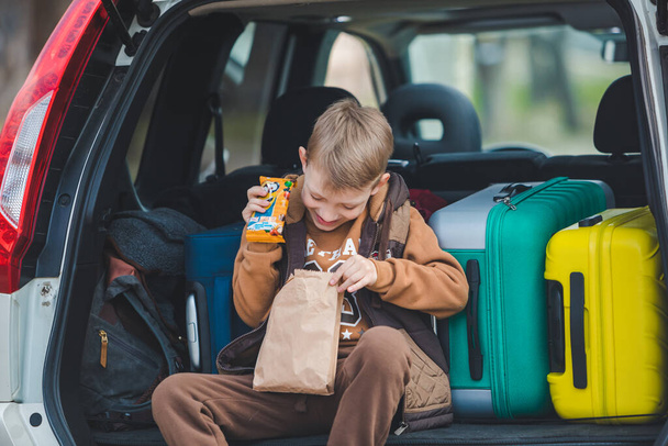petit enfant regardant dans un sac en papier avec des bonbons assis dans le coffre de la voiture - Photo, image