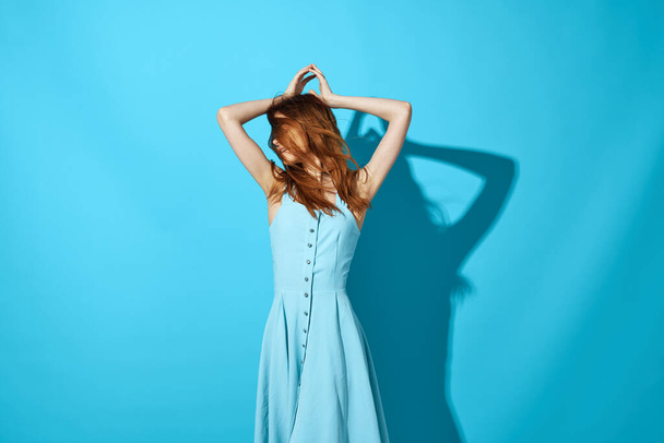cheerful pretty woman holding her hair blue luxury dress Shadow on the background - 写真・画像