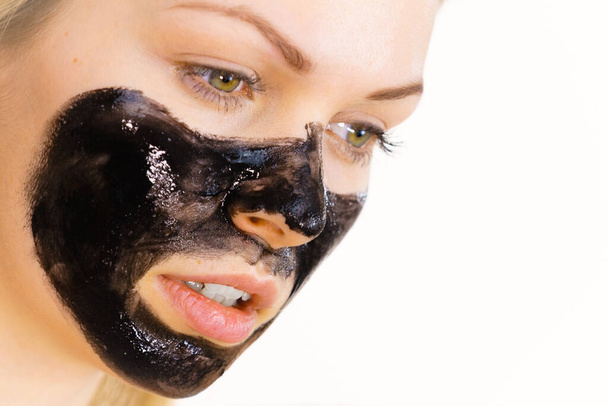 Young woman applying carbo detox black mask to her face. Teen girl taking care of oily skin, cleaning the pores. Spa treatment. Skincare. - Foto, afbeelding