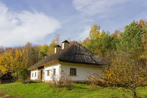 Altes ukrainisches Holzbauernhaus mit Reetdach aus dem 19. Jahrhundert, Herbsttag. Pyrohiv, Kiew, Ukraine - Foto, Bild