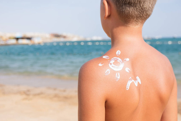 Écran solaire sous forme de soleil et de vagues sur la peau du garçon Journée ensoleillée d'été pour le voyage en mer - Photo, image