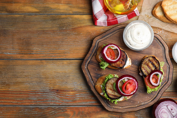 Delicious eggplant sandwiches served on wooden table, flat lay. Space for text - Foto, afbeelding