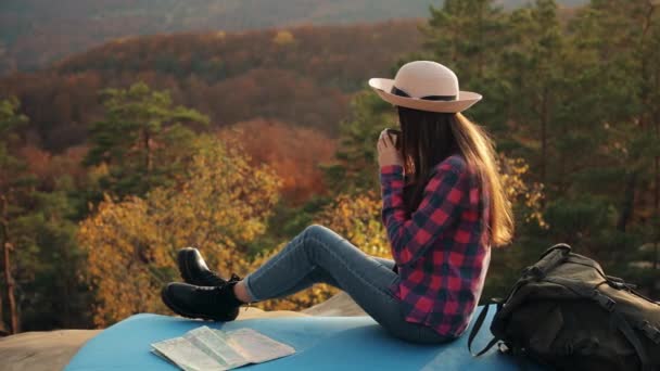 Μια νεαρή γυναίκα πίνει ζεστό τσάι. Κάθεται πάνω σε μια πέτρα. Πεζοπορία στα βουνά. 4K - Πλάνα, βίντεο