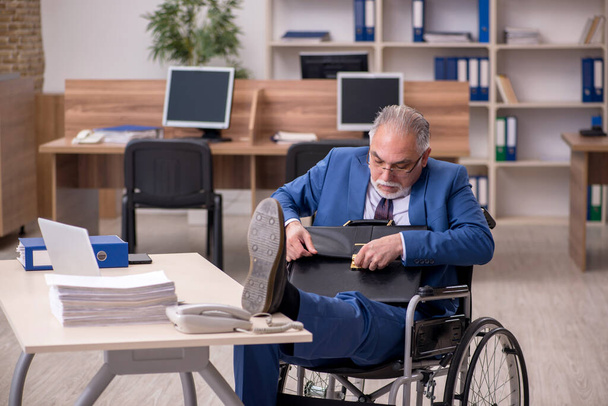 Stary pracownik biznesowy na wózku inwalidzkim pracujący w biurze - Zdjęcie, obraz