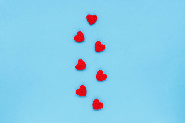 Ornament of red hearts on a blue background, top view, flat lay. Valentines day concept. - 写真・画像