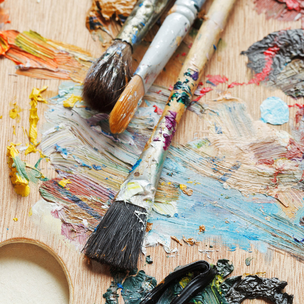 few paintbrushes on used artistic pallette - Foto, afbeelding