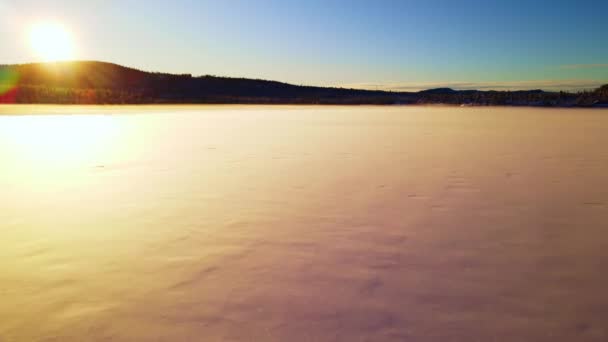 Let nad zamrzlým jezerem pokrytým šumivým sněhem v arktické divočině během západu slunce. - Záběry, video