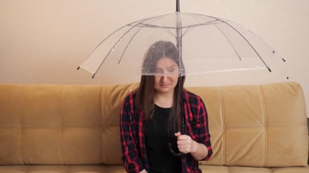 Pensive vrouw verbergt zich voor stromend water onder heldere paraplu - Video