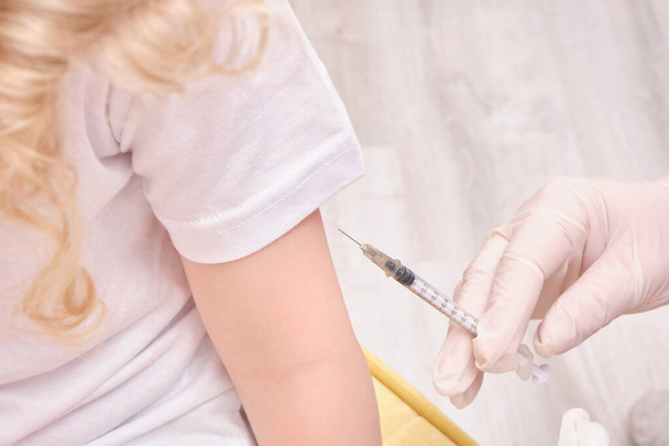 A doctor makes a vaccination to a child - Foto, afbeelding