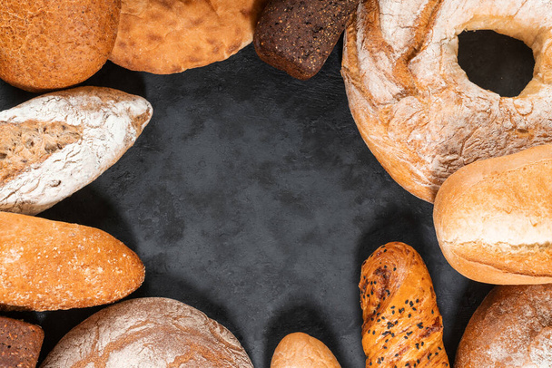 Different types of bread on a dark wooden background - Φωτογραφία, εικόνα