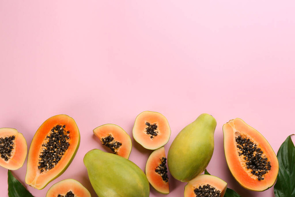 Fresh ripe papaya fruits with green leaves on pink background, flat lay. Space for text - Fotografie, Obrázek