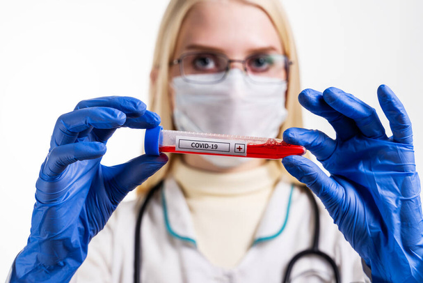 Nurse wearing respirator mask holding a positive blood test result for the new rapidly spreading Coronavirus, originating in Wuhan, China - Φωτογραφία, εικόνα