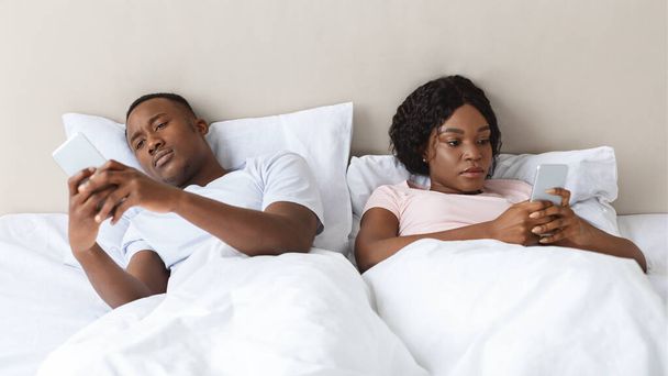Uomo e donna indifesi sdraiati a letto, usando i loro smartphone - Foto, immagini