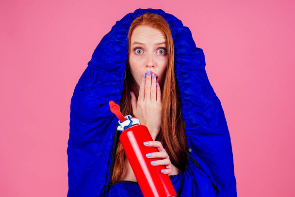 redhair ginger woman holding red thermos and wrapped in in sleeping bag - Photo, image