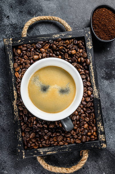 Coffee cup and beans in old wooden tray. Black background. Top view - Photo, Image