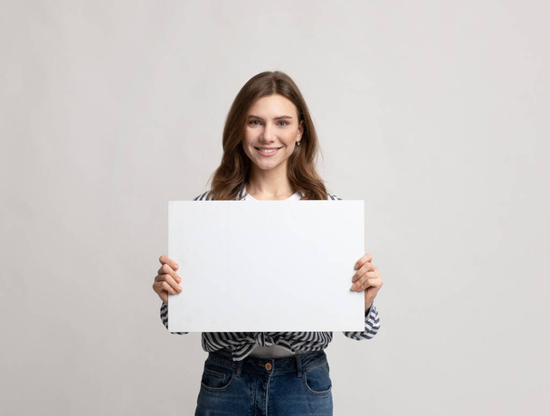 Mooie jonge vrouw Holding Blanco Placard met kopieerruimte voor reclame - Foto, afbeelding