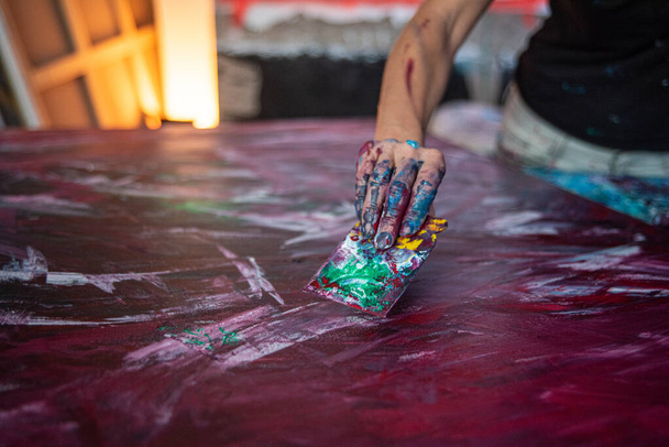 se puede ver la mano de una joven pintora con una herramienta que utiliza para pintar cuadros en su estudio, centrarse en las manos - Foto, imagen
