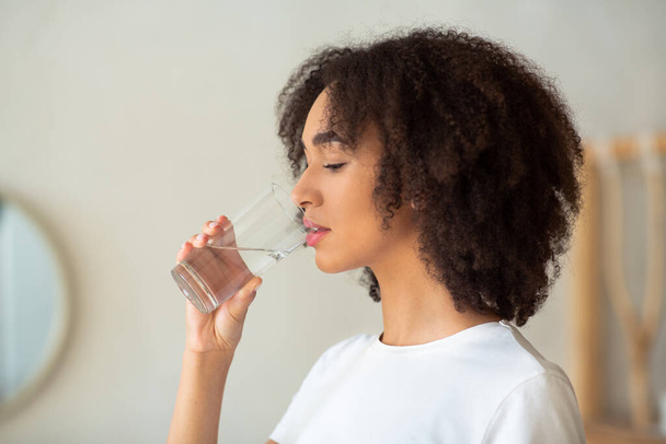 Thirsty woman holds glass drinks still water preventing dehydration - Photo, Image