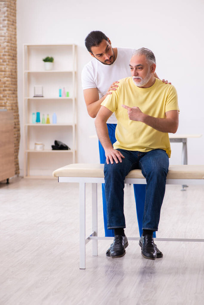 Old male patient visiting young male doctor chiropractor - Photo, Image