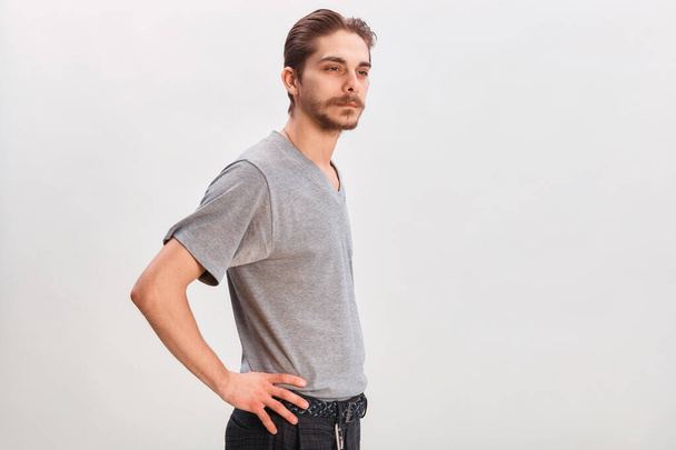 人々の概念-ひげを生やした顔の男。灰色のシャツを着た優しい若い男がグレーの背景にカメラを見ている。スペースのコピー - 写真・画像