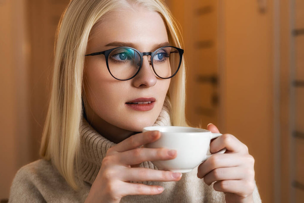 Young beautiful girl sitting in a coffee shop with a mug of tea - Φωτογραφία, εικόνα