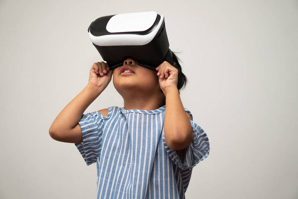 Little Asian girl child with virtual reality headset is exciting for new experiencing. Concept of 3D gadget technology and virtual world gadgets game and online education in the future - Photo, image