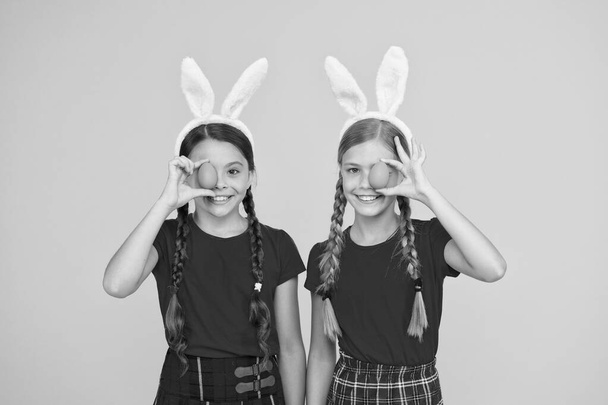 spring is coming. happy childhood concept. small girls bunny ears yellow background. funny little sister kids celebrate easter. egg hunt begin. traditional spring holiday. happy easter - Zdjęcie, obraz
