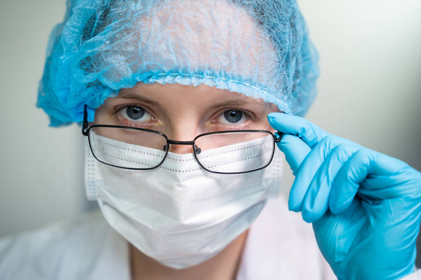 Young girl doctor looks at you with her glasses down - Фото, зображення