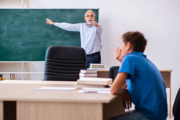 Old male teacher and schoolboy in the classroom - 写真・画像