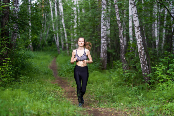 Athletic girl running along the forest path - Fotografie, Obrázek