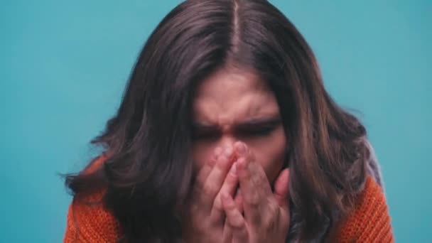 chora kobieta w szaliku kichająca w odizolowanej na niebiesko tkance - Materiał filmowy, wideo