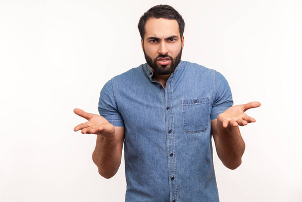 Annoyed stressed man with beard asking what do you want and spreading hands, seriously looking at camera, family quarrel, misunderstanding. Indoor studio shot isolated on white background - 写真・画像