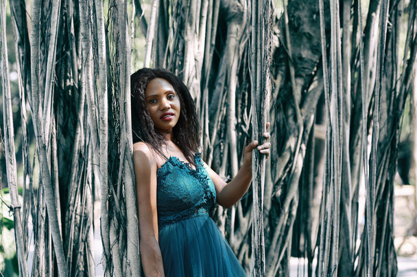 Vrolijke jonge vrouw staat bij de boom in de jungle.  - Foto, afbeelding
